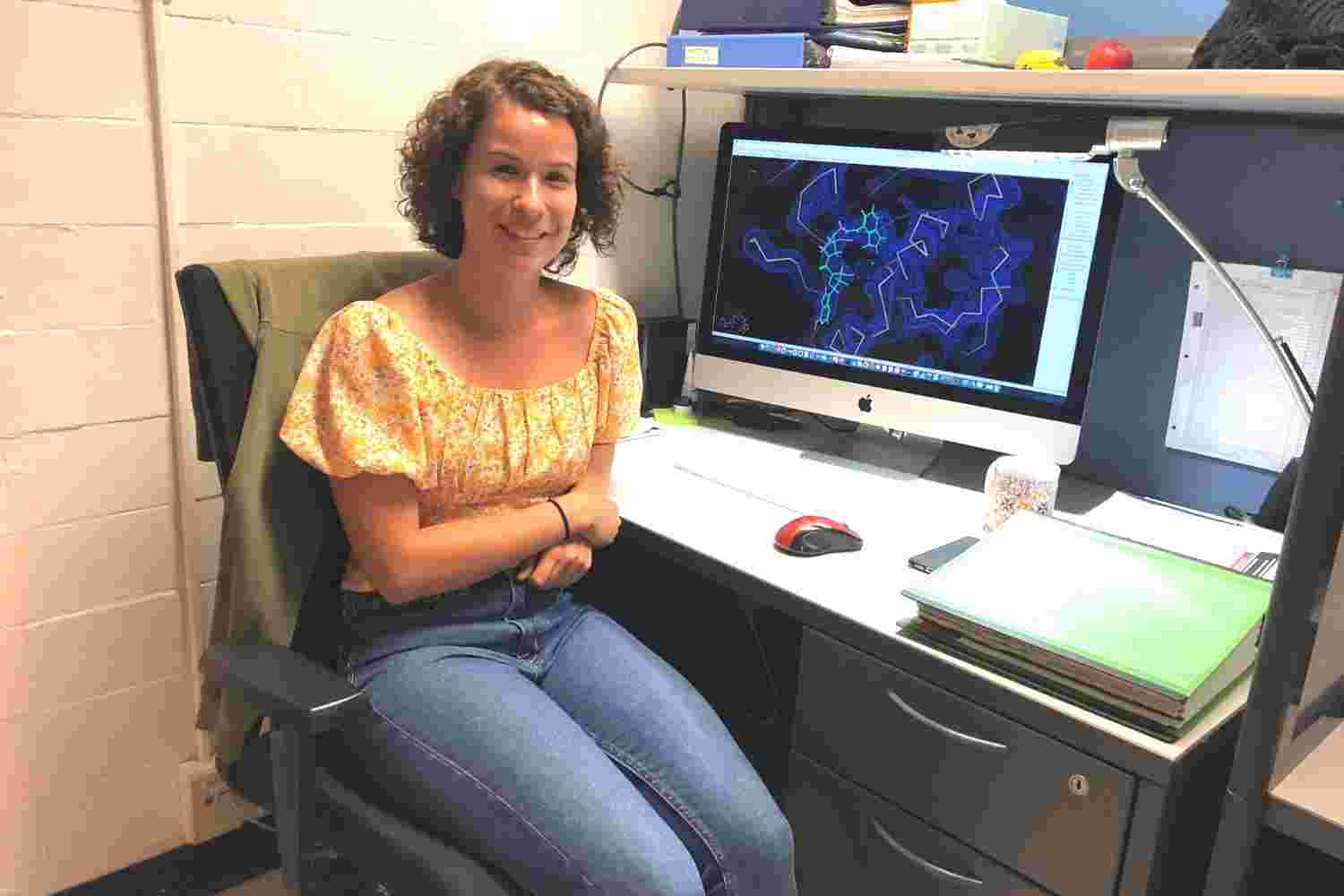 Doctoral candidate Élise Rouleau-Turcotte is pictured next to a computer-generated electron density map and an atomic model of an inhibitor bound to the PARP1 active site.