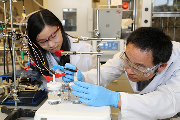 Researchers Xueli Zheng, left, and Bo Zhang test a previous catalyst for the artificial photosynthesis system. The new catalyst works at lower pH, leading to an improvement in the overall efficiency of the system. (Photo: Marit Mitchell)